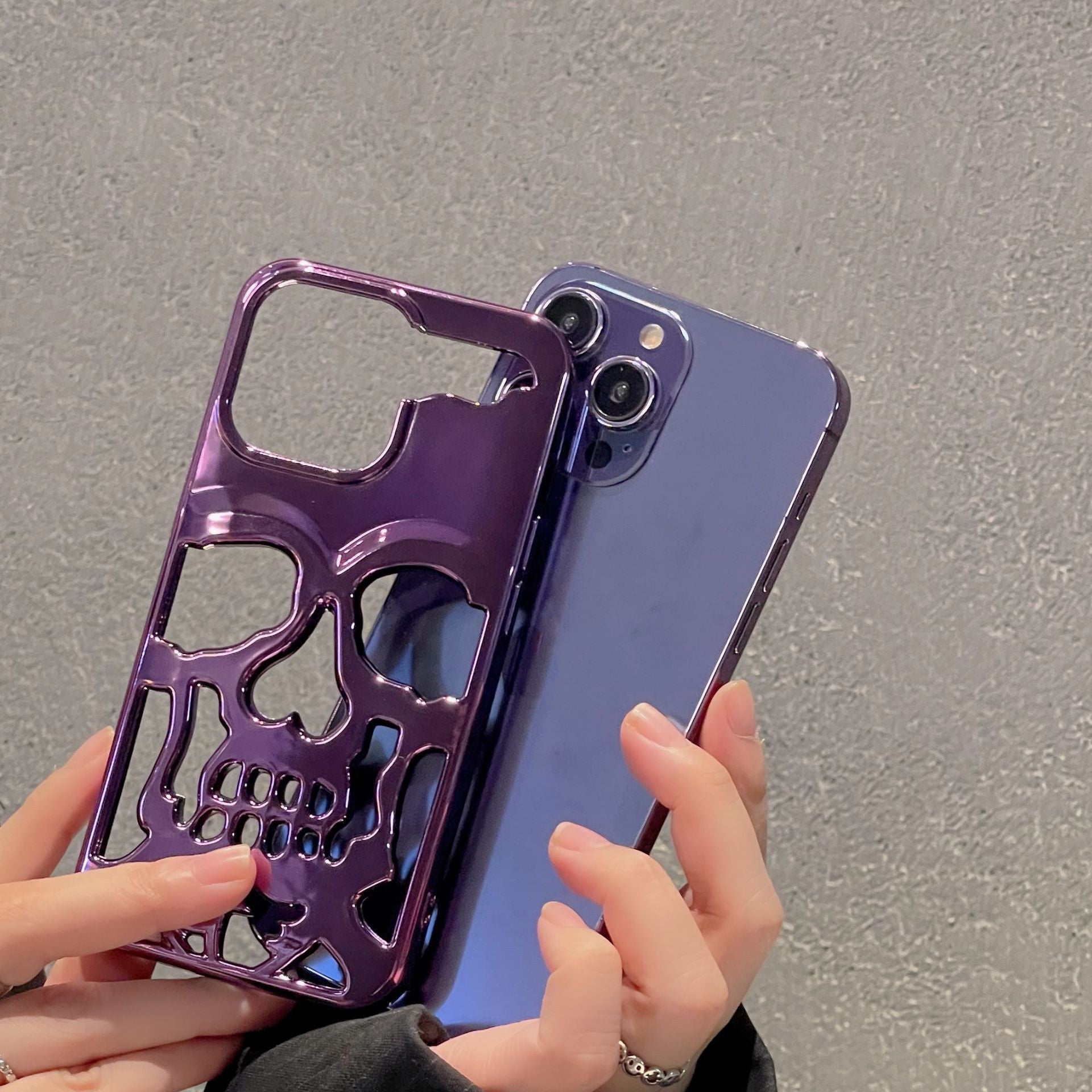 3D skull phone case in purple design held alongside a smartphone for stylish protection