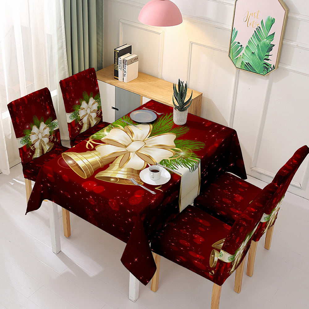 Christmas dining table decor featuring a festive red tablecloth with bells and greenery on a dining table