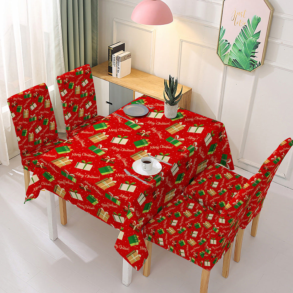 Christmas dining table decor featuring a festive red tablecloth and matching chair covers with holiday designs