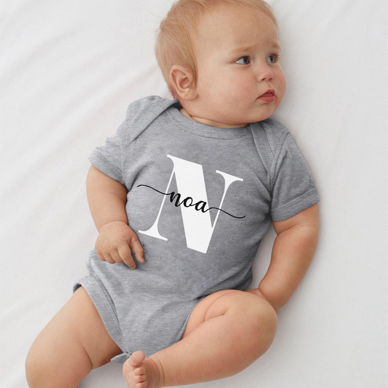 Custom baby name bodysuit in gray featuring a large letter N and the name noa