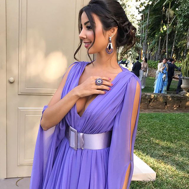 Elegant woman in a purple deep V waist dress for events with stylish accessories in a garden setting