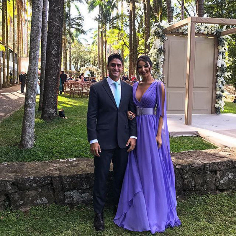 Elegant woman in a purple deep V waist dress for events standing beside a man at a outdoor venue