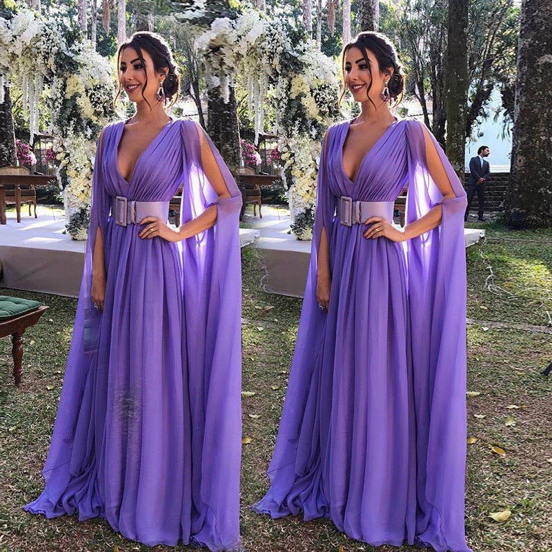 Elegant woman in a purple deep V waist dress for events with flowing cape sleeves and a stylish belt