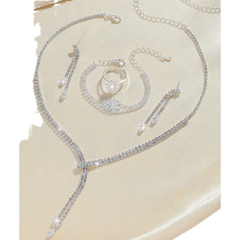 Elegant wedding zirconium jewelry set featuring a necklace, earrings, bracelet, and ring on a soft background